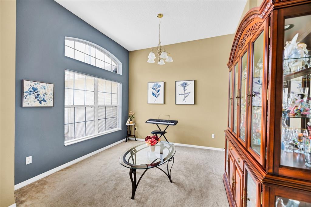 A dining room features a glass coffee table, a keyboard, and a large wooden china cabinet — 7 PHOENIX LANE, PALM COAST, FL