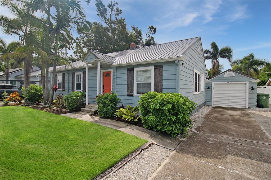 A light blue, single-story house with a metal roof, orange front door, and detached garage — 2321 18TH AVENUE W, BRADENTON, FL