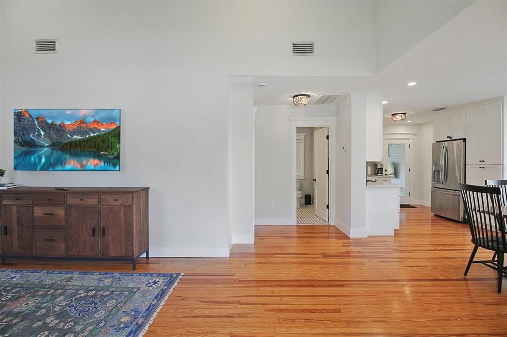 A living area with hardwood floors, a wooden console, and a view into the kitchen — 2321 18TH AVENUE W, BRADENTON, FL