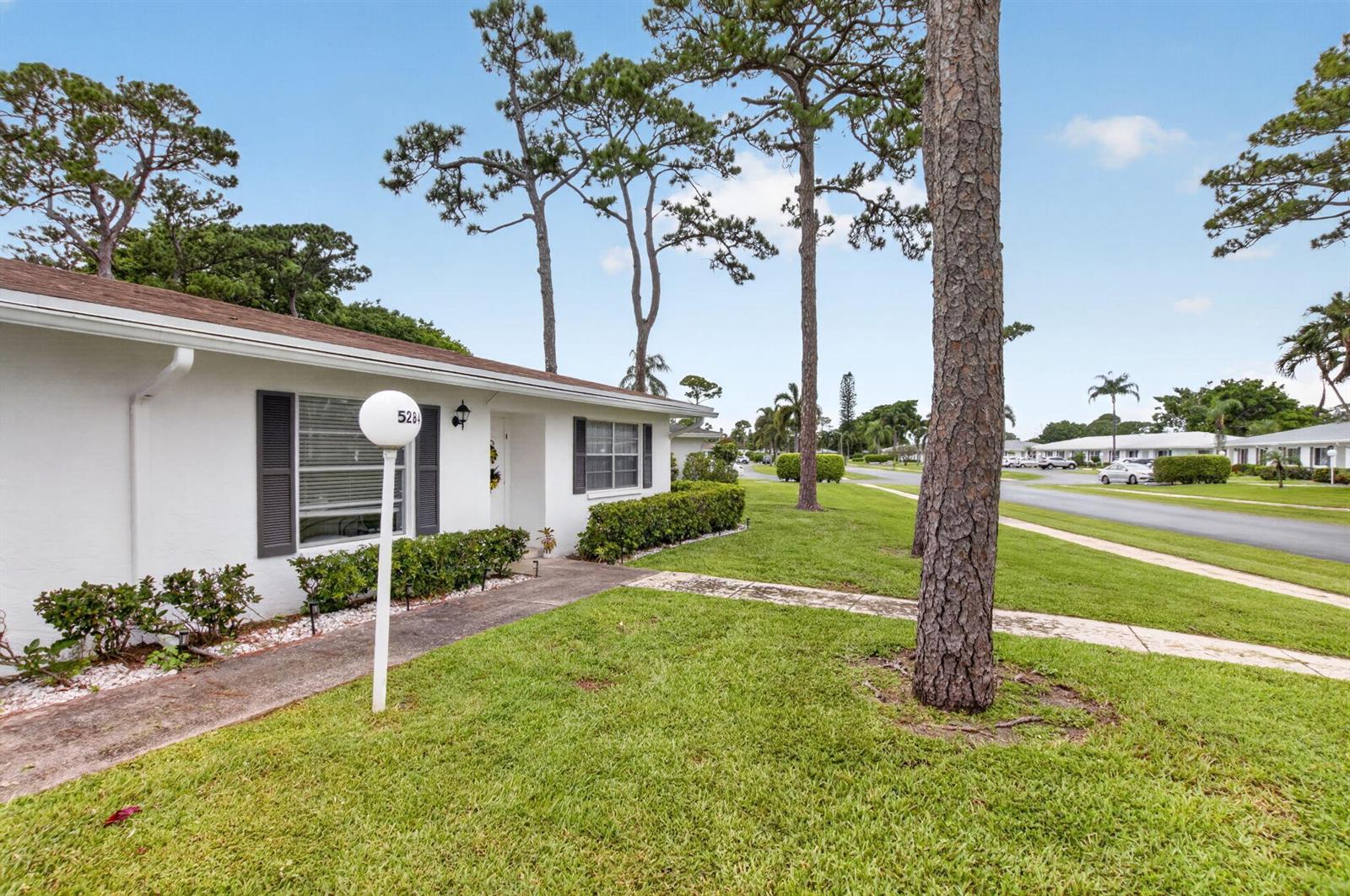 A white single-story house with dark shutters and a lawn with pine trees — 5284 Privet Place # D, Delray Beach FL 33484, DELRAY BEACH, FL
