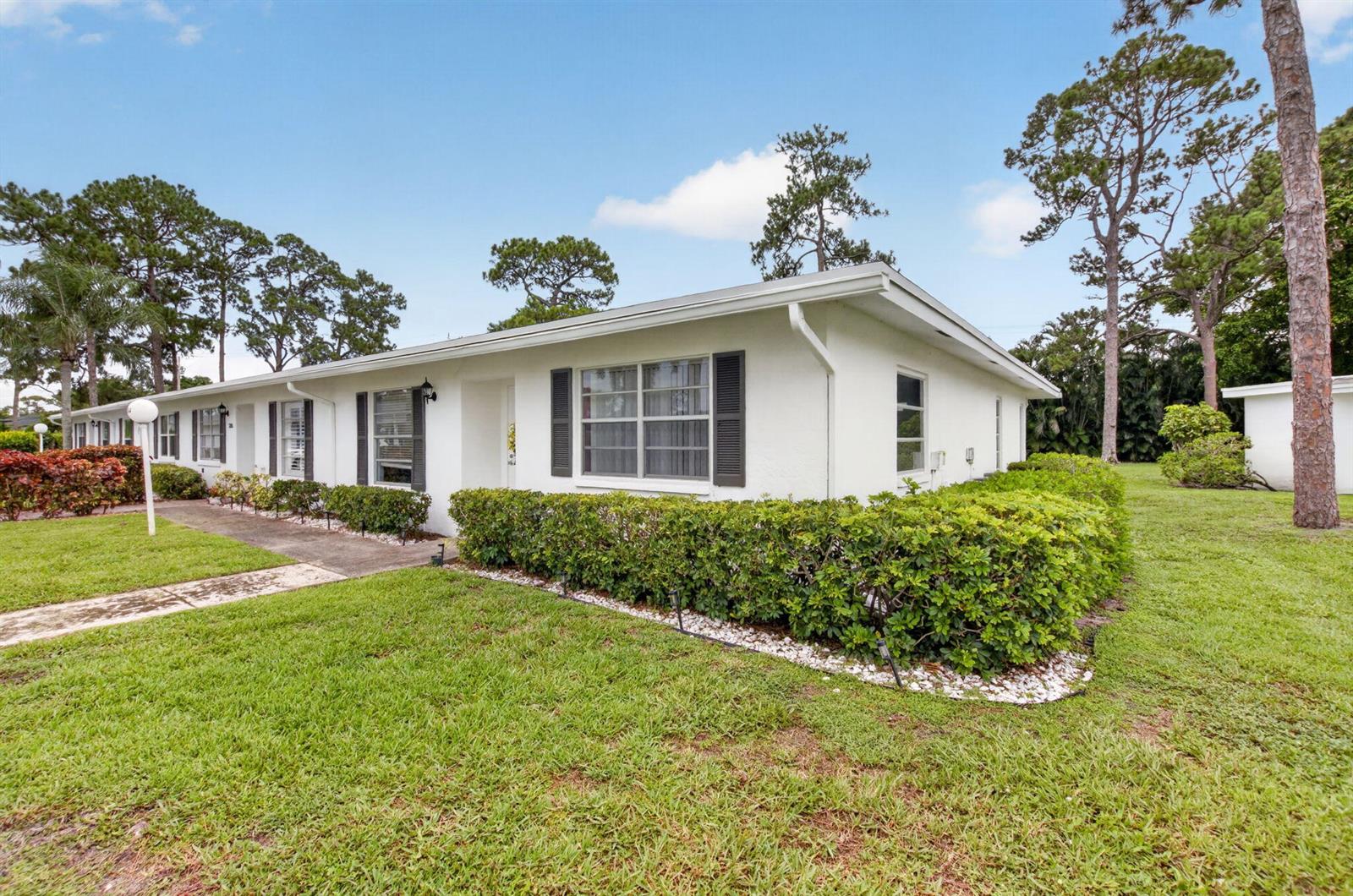 A white single-story residential building features dark shutters, a front walkway, and manicured landscaping — 5284 Privet Place # D, Delray Beach FL 33484, DELRAY BEACH, FL