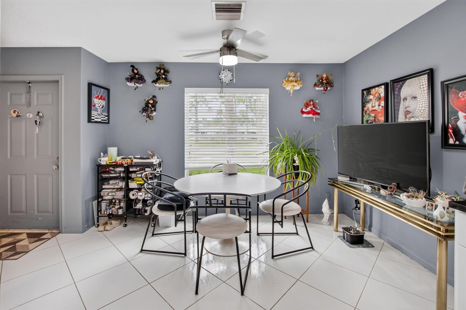 A dining area with a round table, four chairs, gray walls, and wall-mounted doll decor — 5284 Privet Place # D, Delray Beach FL 33484, DELRAY BEACH, FL