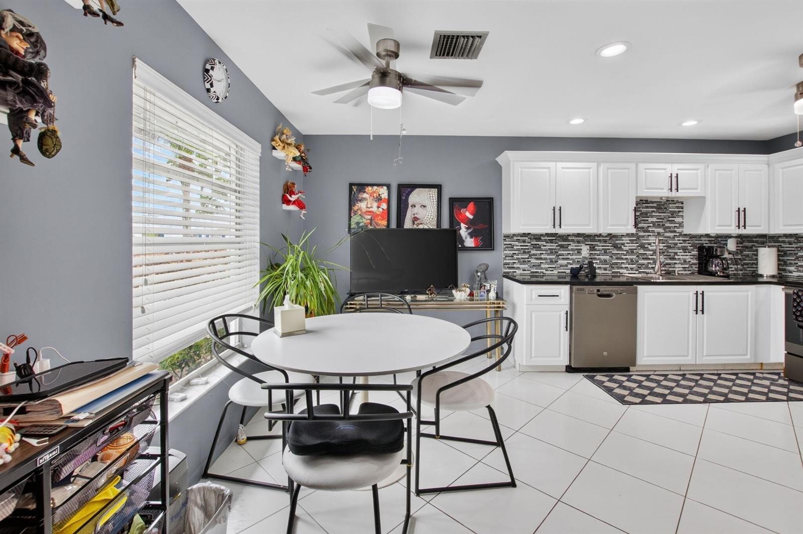 A kitchen and dining area with white cabinets, a round table, and gray walls — 5284 Privet Place # D, Delray Beach FL 33484, DELRAY BEACH, FL