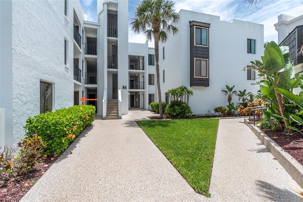 A multi-story white apartment building with a central staircase and a landscaped front yard — 2955 N BEACH ROAD UNIT A411, ENGLEWOOD, FL
