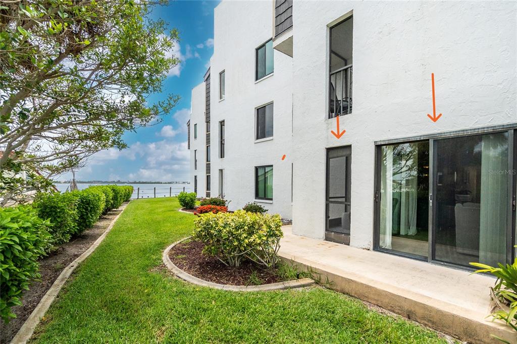 A ground-floor patio with sliding glass doors sits beside a grassy lawn and water view — 2955 N BEACH ROAD UNIT A411, ENGLEWOOD, FL