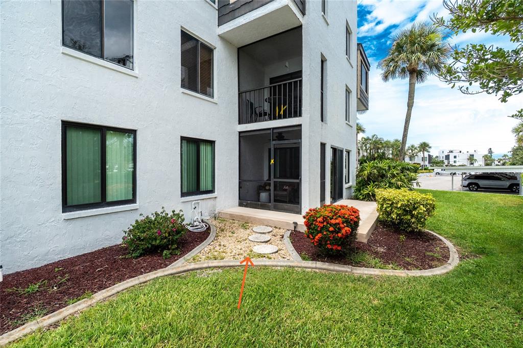 A ground-floor patio with a screened enclosure and stepping stones set in a landscaped garden — 2955 N BEACH ROAD UNIT A411, ENGLEWOOD, FL