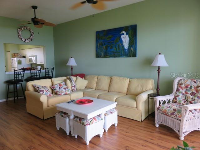 A living room features a yellow sectional sofa, a white coffee table, and a wicker chair — 2625 TERRA CEIA BAY BOULEVARD UNIT 802, PALMETTO, FL