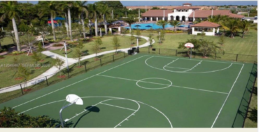 An outdoor basketball court sits in a landscaped community area with a pool and clubhouse — HOMESTEAD, FL