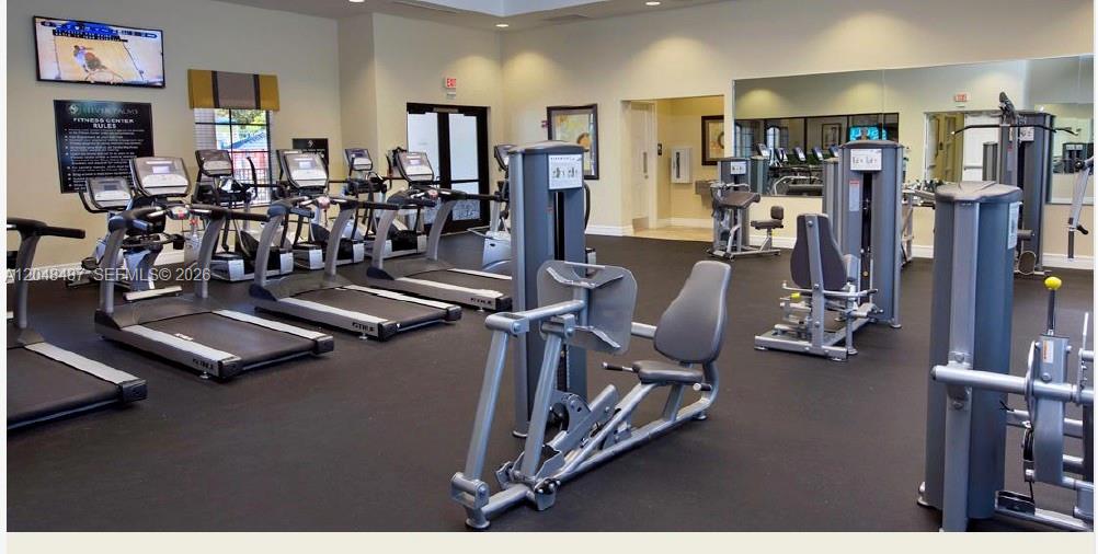 A fitness center features multiple treadmills, weight machines, and a large wall mirror — HOMESTEAD, FL
