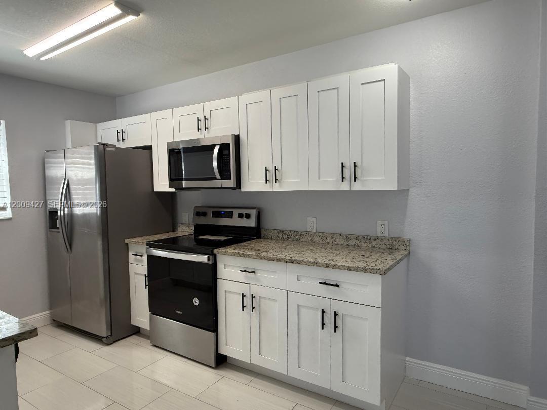 A kitchen features white cabinets, granite countertops, and stainless steel appliances — 2713 NW 6th St, Pompano Beach FL 33069, POMPANO BEACH, FL