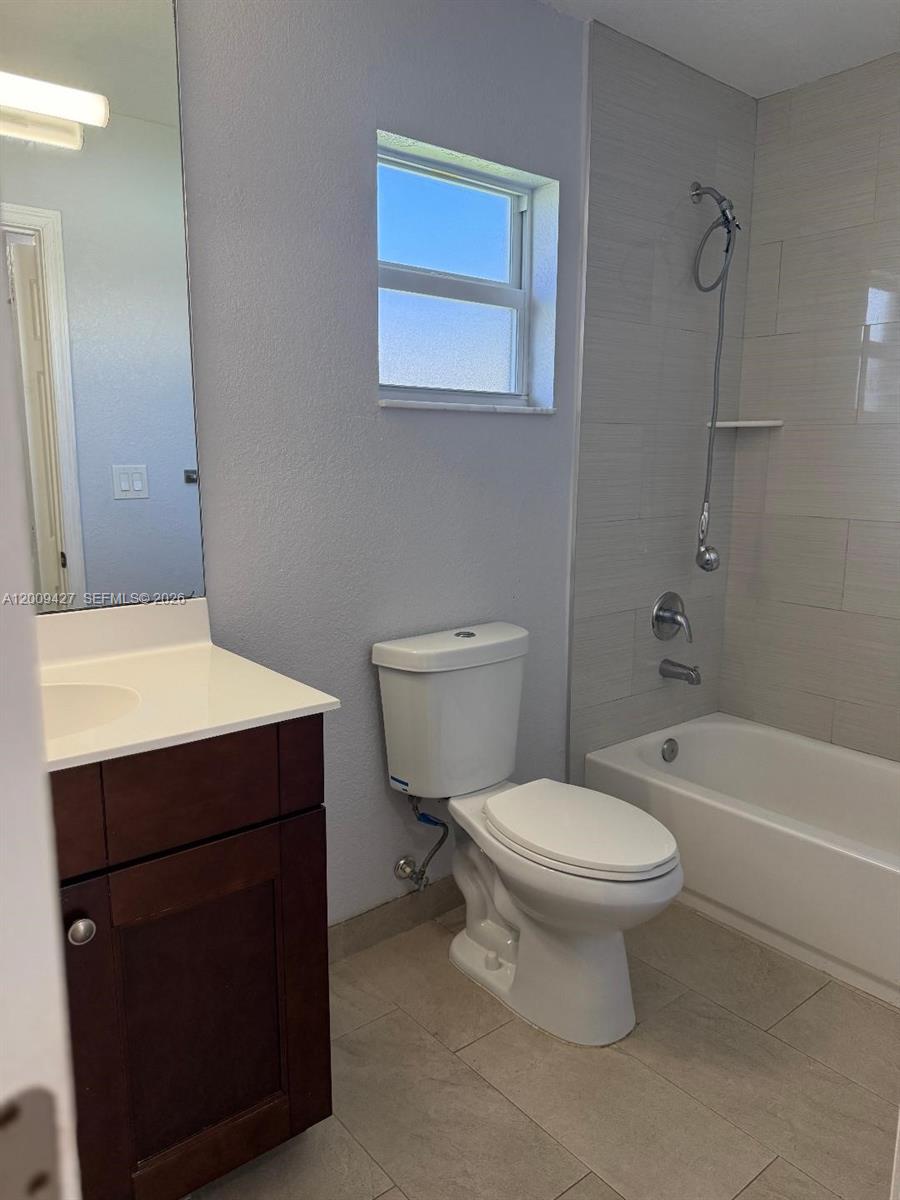 A bathroom features a dark wood vanity, a white toilet, and a tiled shower-tub combination — 2713 NW 6th St, Pompano Beach FL 33069, POMPANO BEACH, FL