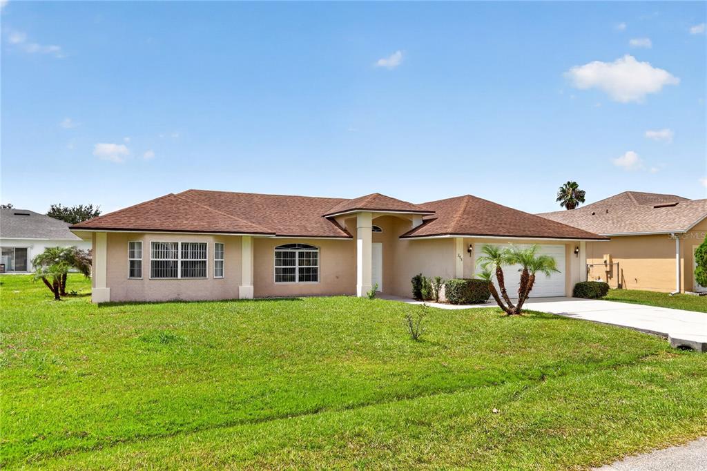 A single-story beige house with a brown shingled roof and a two-car garage — 308 CLERMONT DRIVE, KISSIMMEE, FL