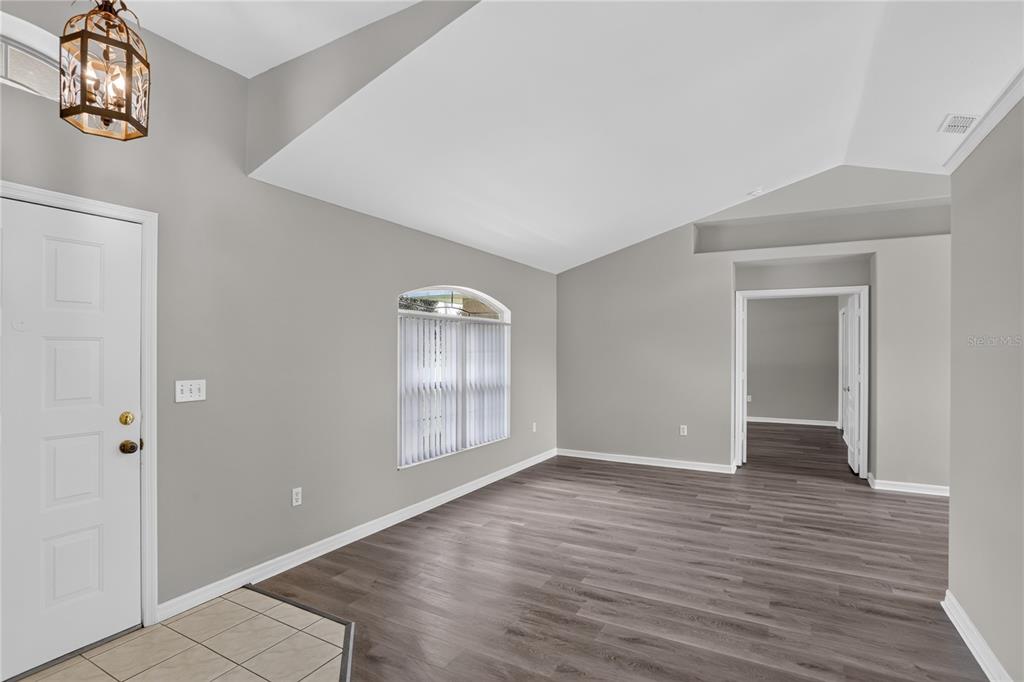 An empty room with gray walls, vaulted ceilings, and dark wood-look flooring — 308 CLERMONT DRIVE, KISSIMMEE, FL