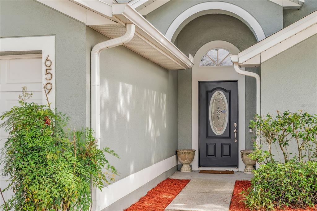 The front entrance of a house features a dark door with a glass oval insert — 659 RESTON PLACE, DAVENPORT, FL
