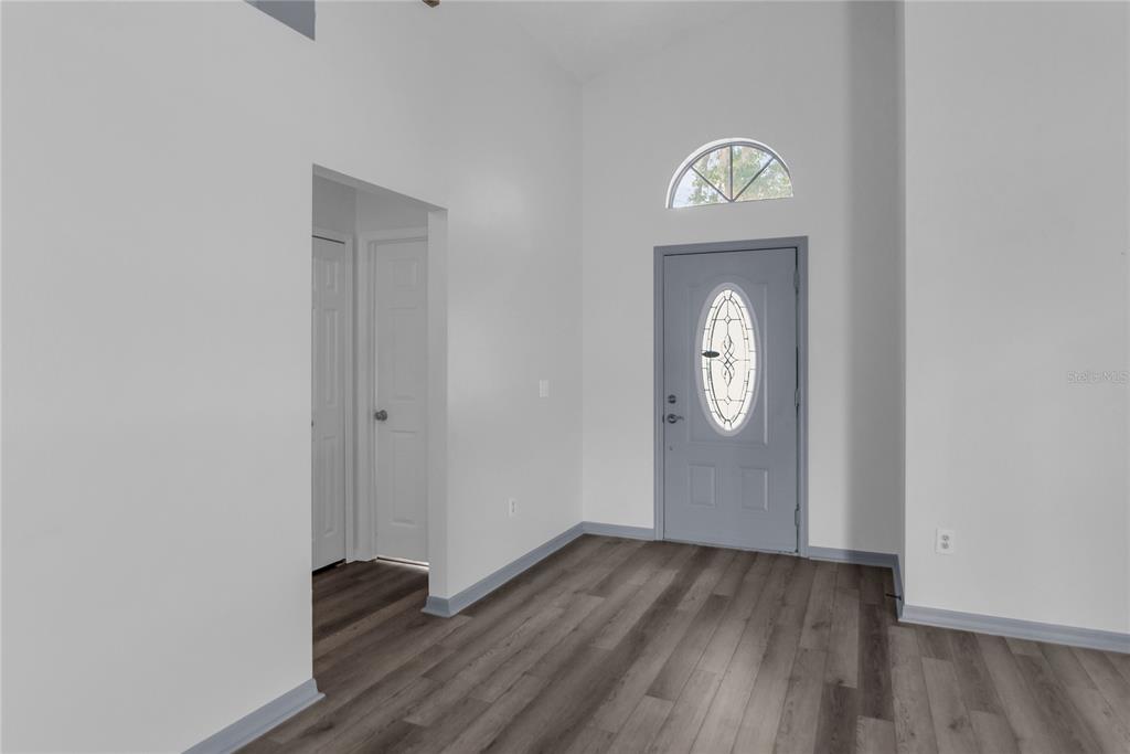 An entryway with high ceilings, grey wood-look flooring, and a grey front door with glass — 659 RESTON PLACE, DAVENPORT, FL