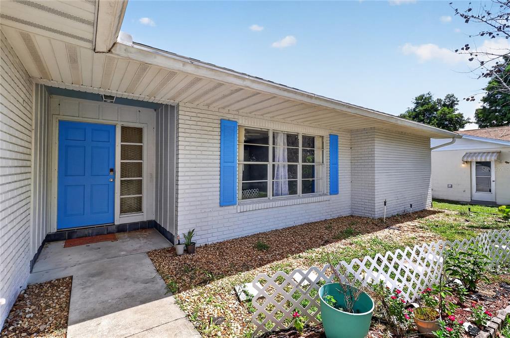 A white brick house exterior features a bright blue front door and matching window shutters — 118 BROWNING CIRCLE, WINTER HAVEN, FL