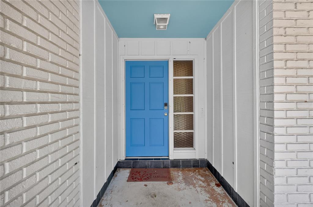 A blue front door is set within a recessed entryway flanked by white brick walls — 118 BROWNING CIRCLE, WINTER HAVEN, FL