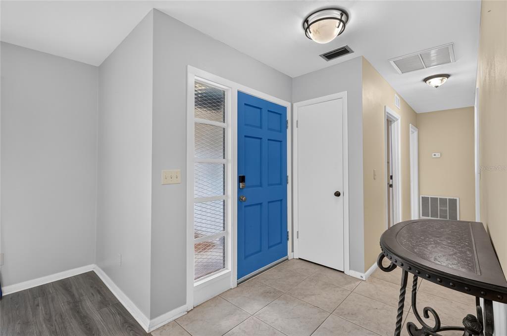 An entryway features a bright blue front door, light gray walls, and beige tile flooring — 118 BROWNING CIRCLE, WINTER HAVEN, FL