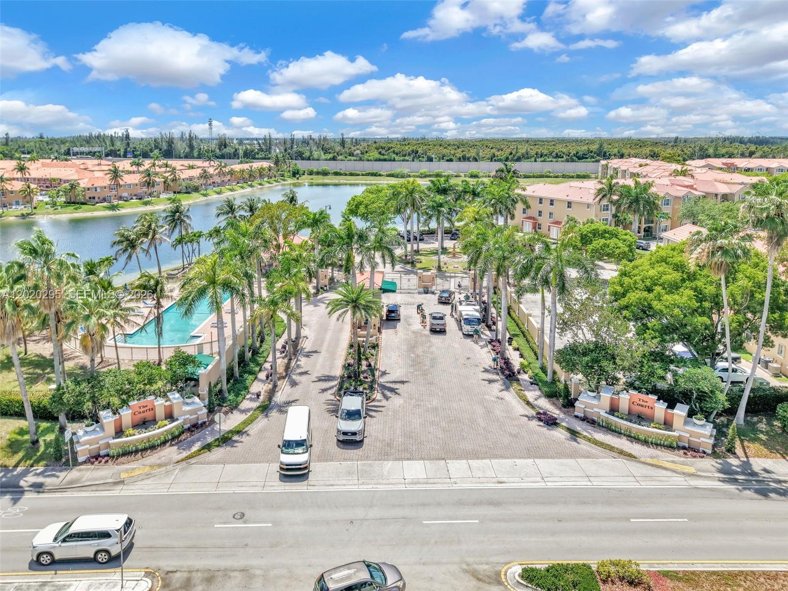 An aerial view shows the gated entrance to a residential community with a swimming pool — 6630 NW 114th Ave # 1538, Doral FL 33178, DORAL, FL