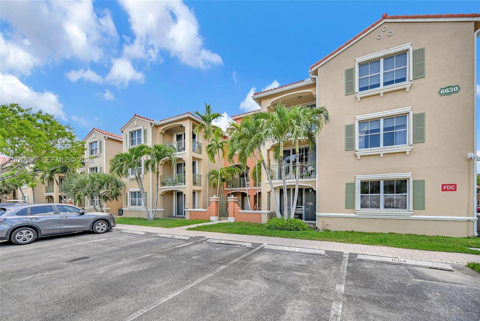 A multi-story apartment building with tan stucco walls, green shutters, and a parking lot — 6630 NW 114th Ave # 1538, Doral FL 33178, DORAL, FL