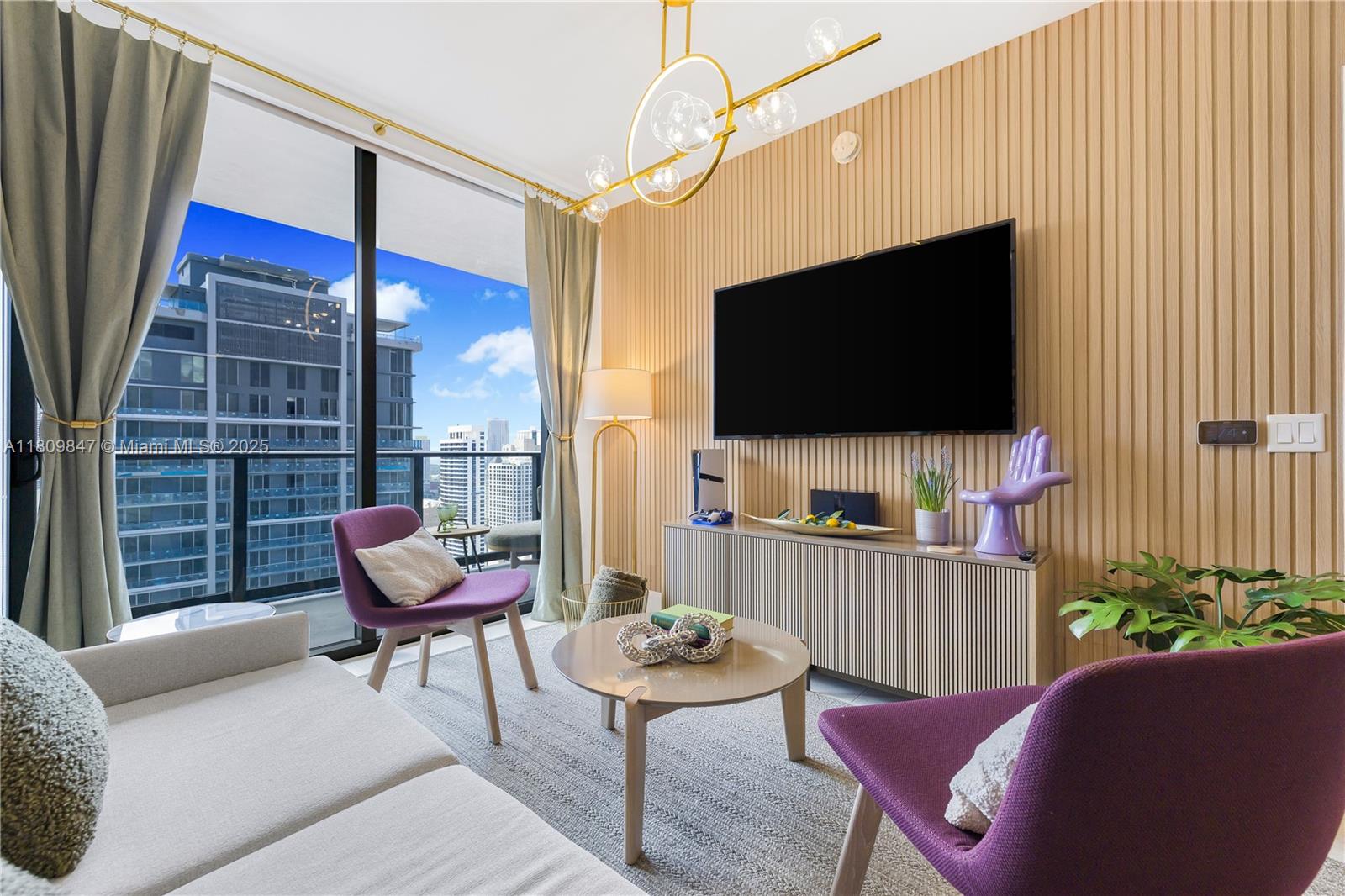 A living room features a slatted wood wall, purple accent chairs, and floor-to-ceiling windows — 159 NE 6th St # 3005, Miami FL 33132, MIAMI, FL