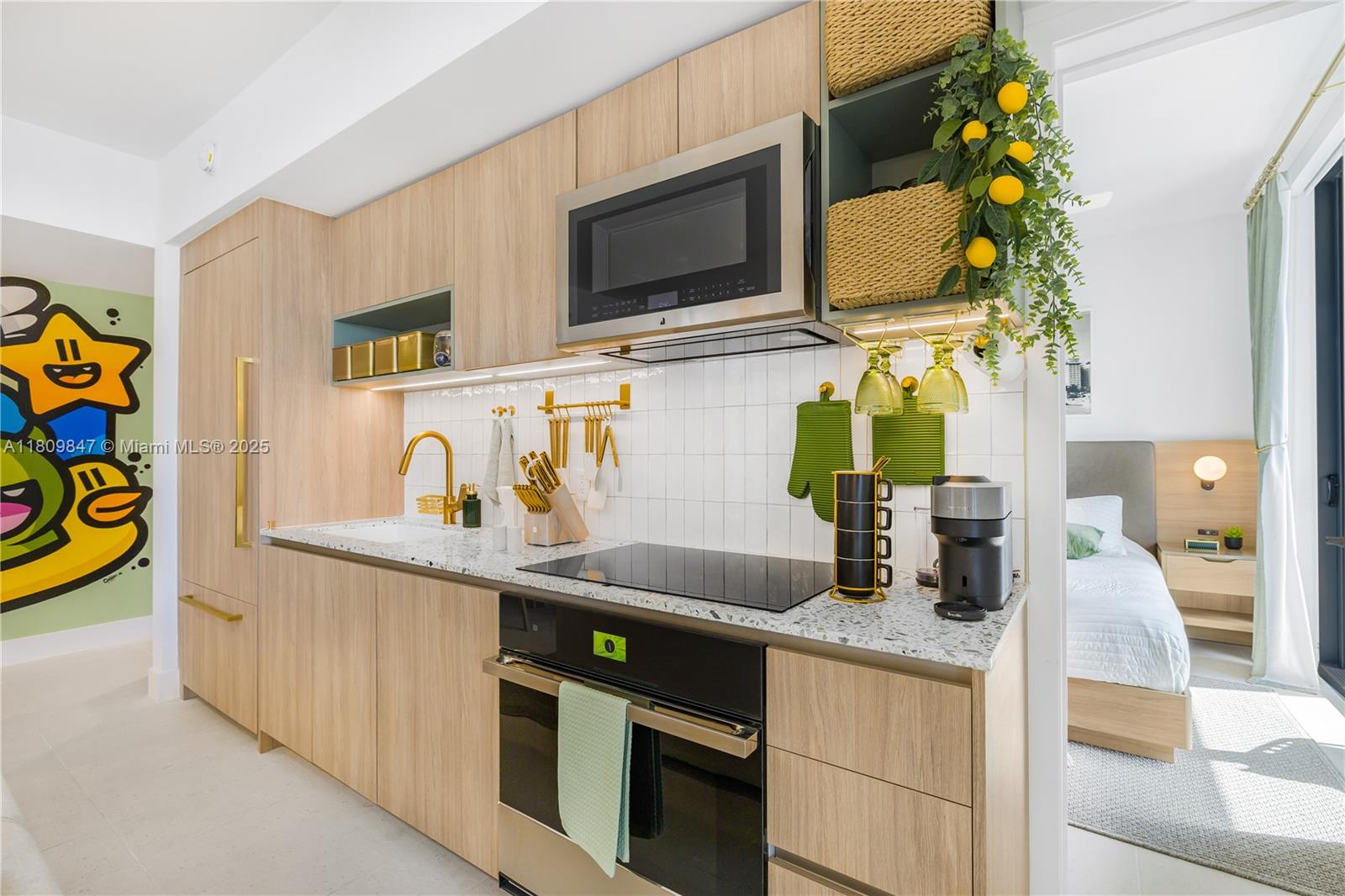 A modern kitchen features light wood cabinets, gold hardware, a speckled countertop, and integrated appliances — 159 NE 6th St # 3005, Miami FL 33132, MIAMI, FL