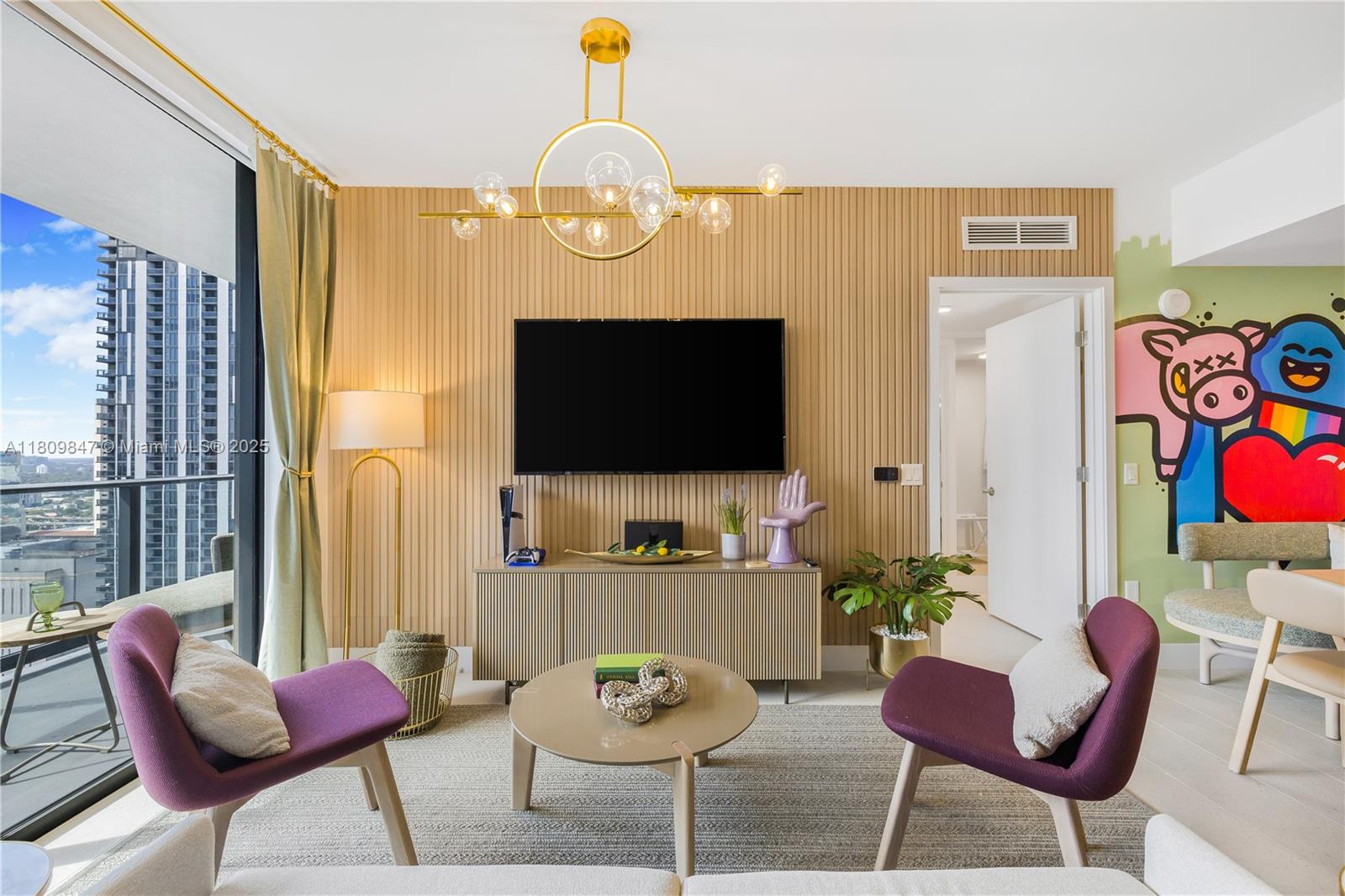 A living room features purple armchairs, a slatted wood wall, a television, and a mural — 159 NE 6th St # 3005, Miami FL 33132, MIAMI, FL
