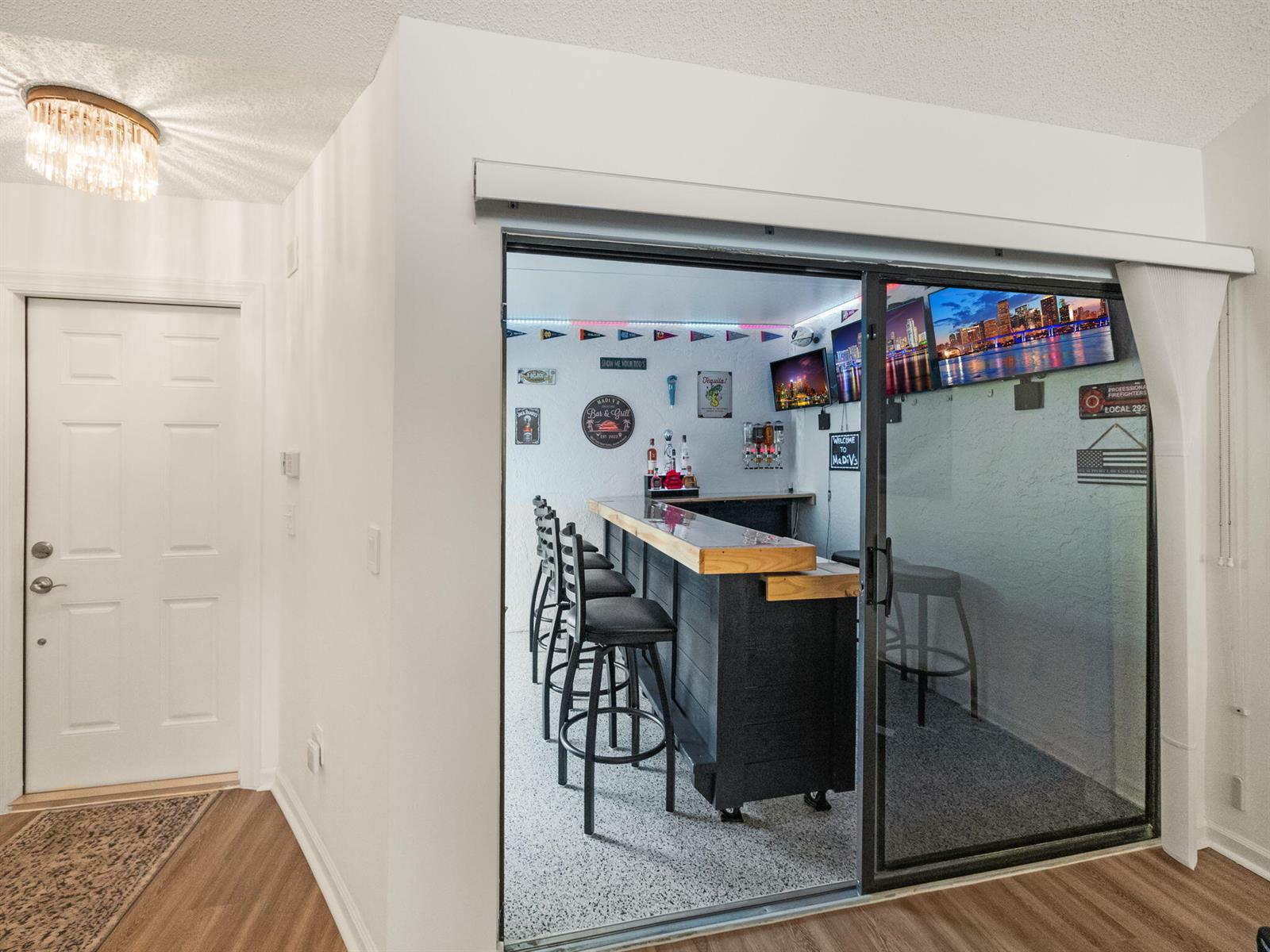 A home bar with stools and a television is visible through a sliding glass door — 1103 Landings Boulevard, FL 33413, FL