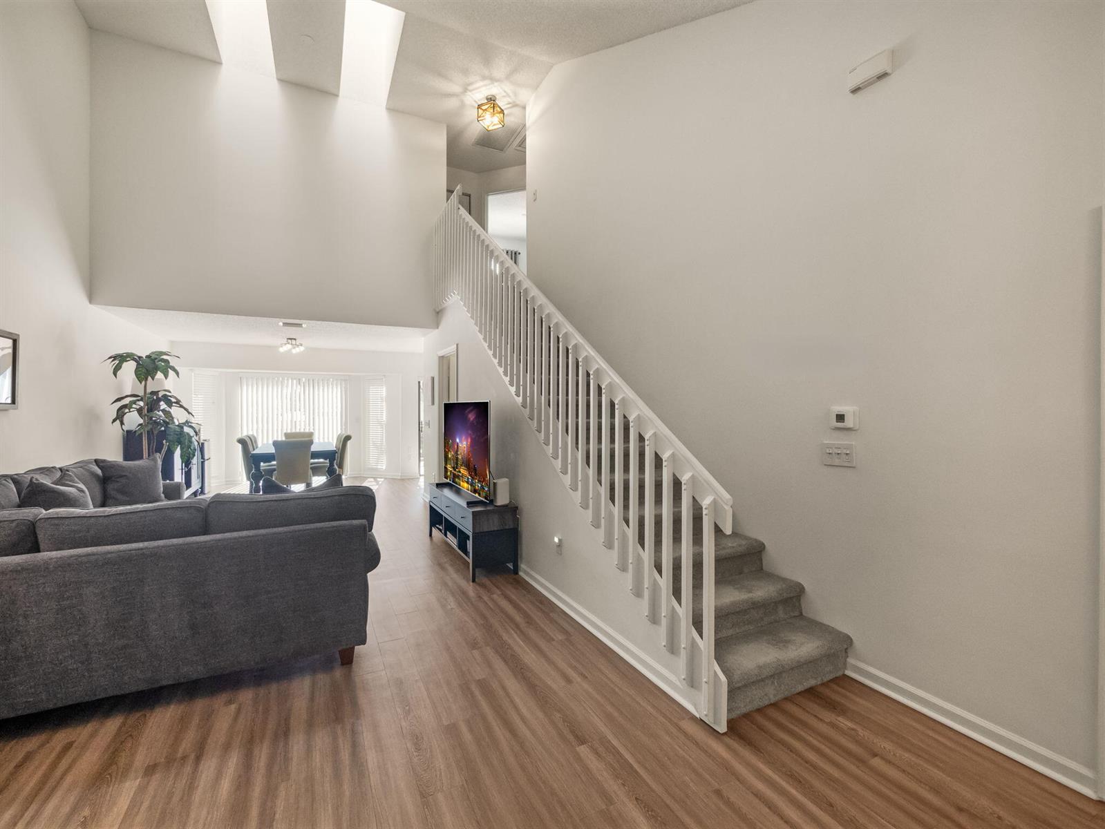 A living room with wood-look flooring, a gray sectional, and stairs with white railings — 1103 Landings Boulevard, FL 33413, FL