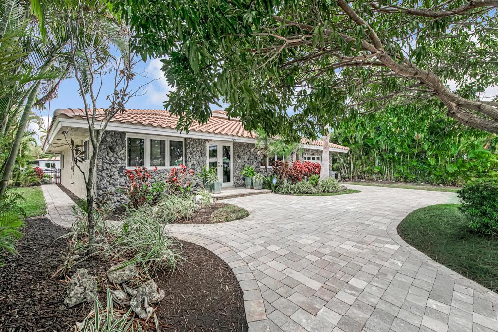 A stone-faced house with a tiled roof and a paved driveway surrounded by lush landscaping — 491 SE 16th Avenue, Pompano Beach FL 33060, POMPANO BEACH, FL