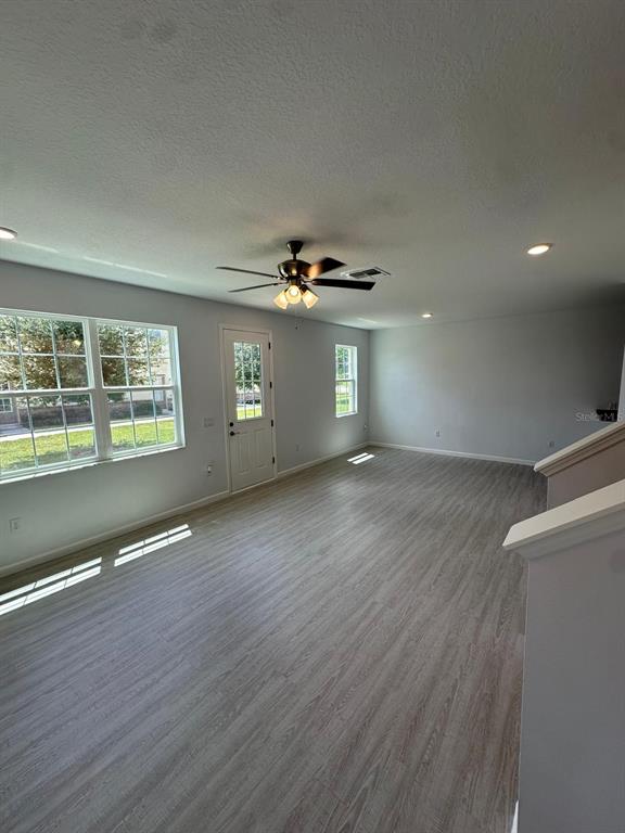 A spacious room with light wood-look flooring, a ceiling fan, and a glass-paneled door — 112 HOLLY VILLAGE DRIVE, DAVENPORT, FL