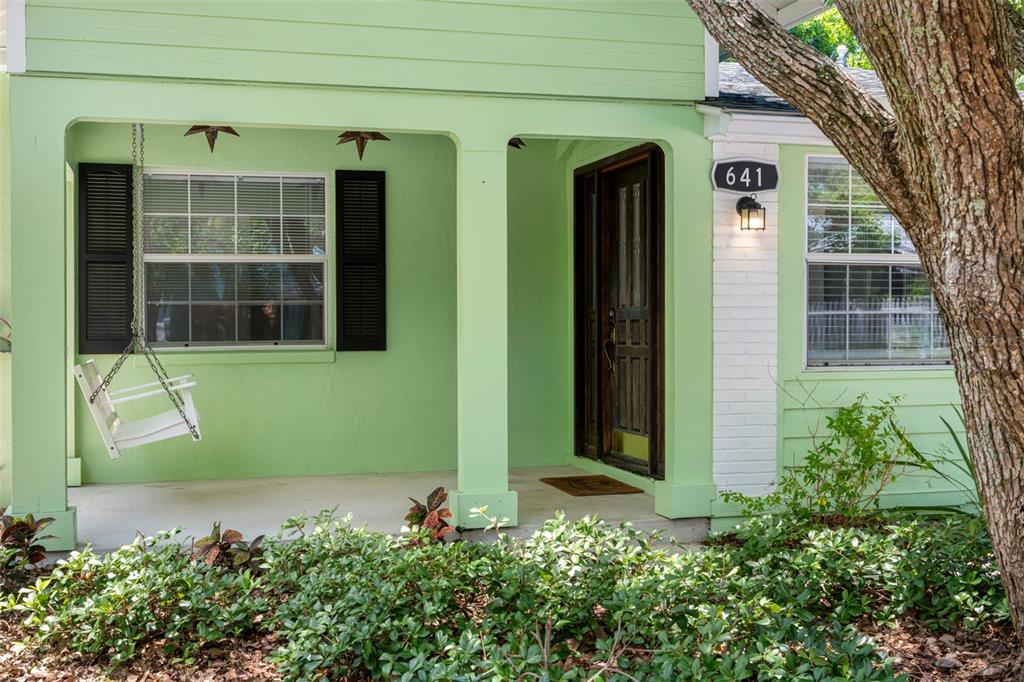 A light green house exterior features a front porch with a white swing and door — 641 WILKIE STREET, DUNEDIN, FL