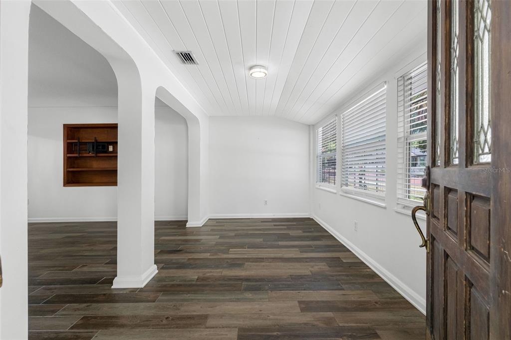 A bright room features white walls, a plank ceiling, and dark wood-look flooring — 641 WILKIE STREET, DUNEDIN, FL