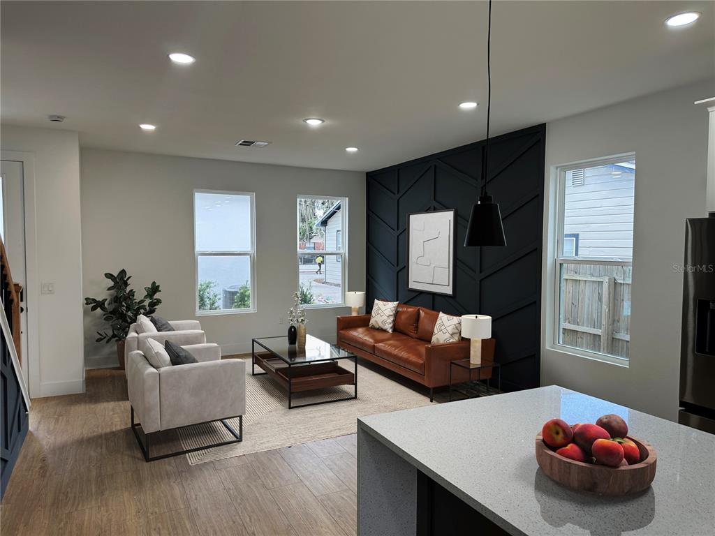 A living room features a black accent wall, leather sofa, two armchairs, and wood flooring — 1317 E HARDING STREET, ORLANDO, FL