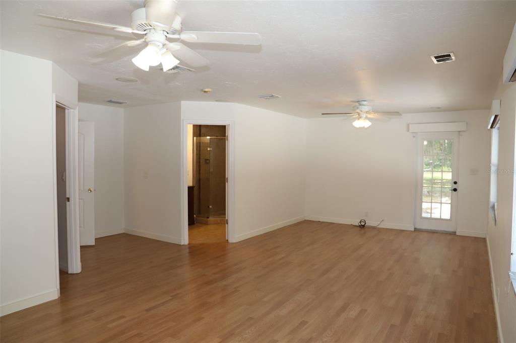 A spacious room with light wood flooring, two ceiling fans, and a glass-paned exterior door — 2810 61ST STREET, SARASOTA, FL