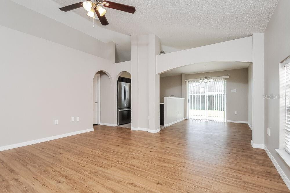 An open living area features light-colored walls, wood-look flooring, arched doorways, and a ceiling fan — 30250 RATTANA COURT, WESLEY CHAPEL, FL
