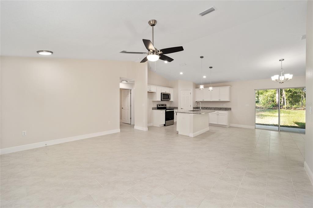 An open-concept kitchen and living area features white cabinets, granite countertops, and tile flooring — 2398 W DEVON DRIVE, CITRUS SPRINGS, FL