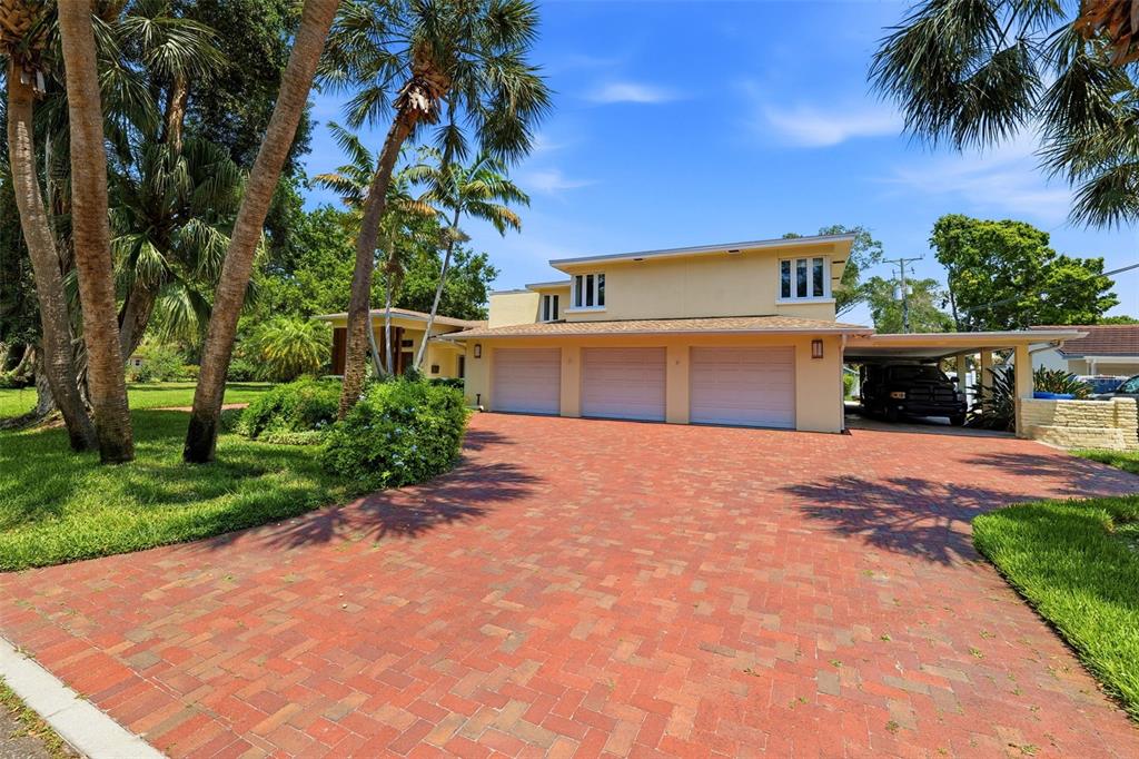 A multi-story house with a three-car garage and a brick driveway surrounded by palm trees — 6000 2ND STREET S, ST PETERSBURG, FL