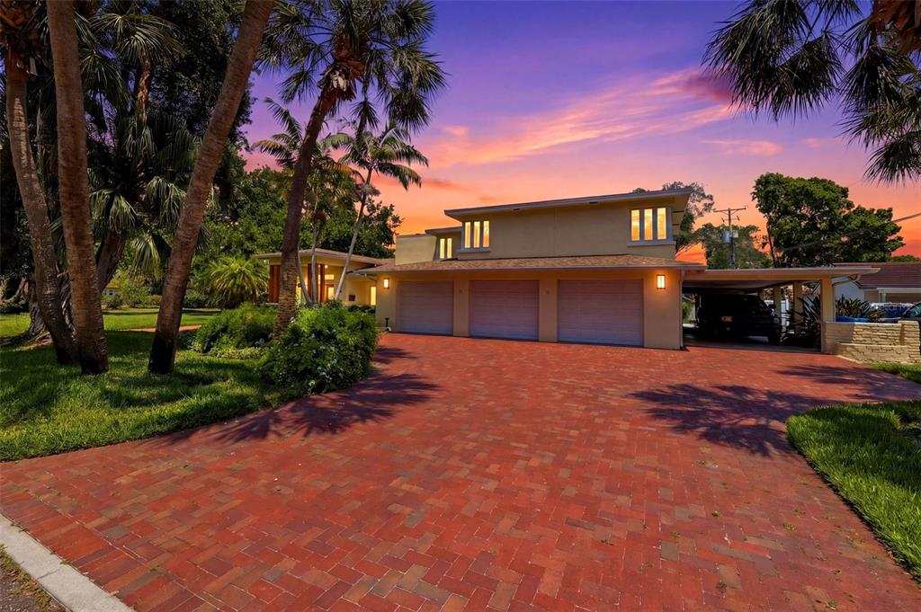 A three-car garage and carport are attached to a two-story house with a brick driveway — 6000 2ND STREET S, ST PETERSBURG, FL