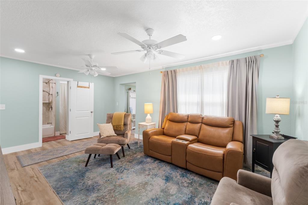 A living room features light blue walls, a brown leather sofa, and two ceiling fans — 309 3RD STREET, MERRITT ISLAND, FL