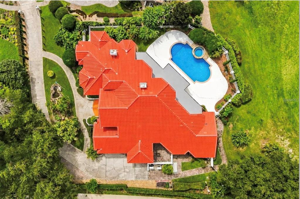 An aerial view shows a house with a red tile roof, pool, and surrounding landscaping — 1036 GOLF VALLEY DRIVE, APOPKA, FL