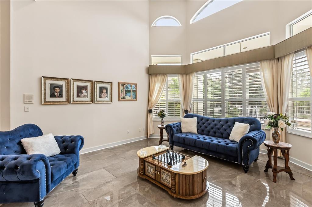 A living room features blue tufted sofas, a chess table, and large windows with shutters — 1036 GOLF VALLEY DRIVE, APOPKA, FL