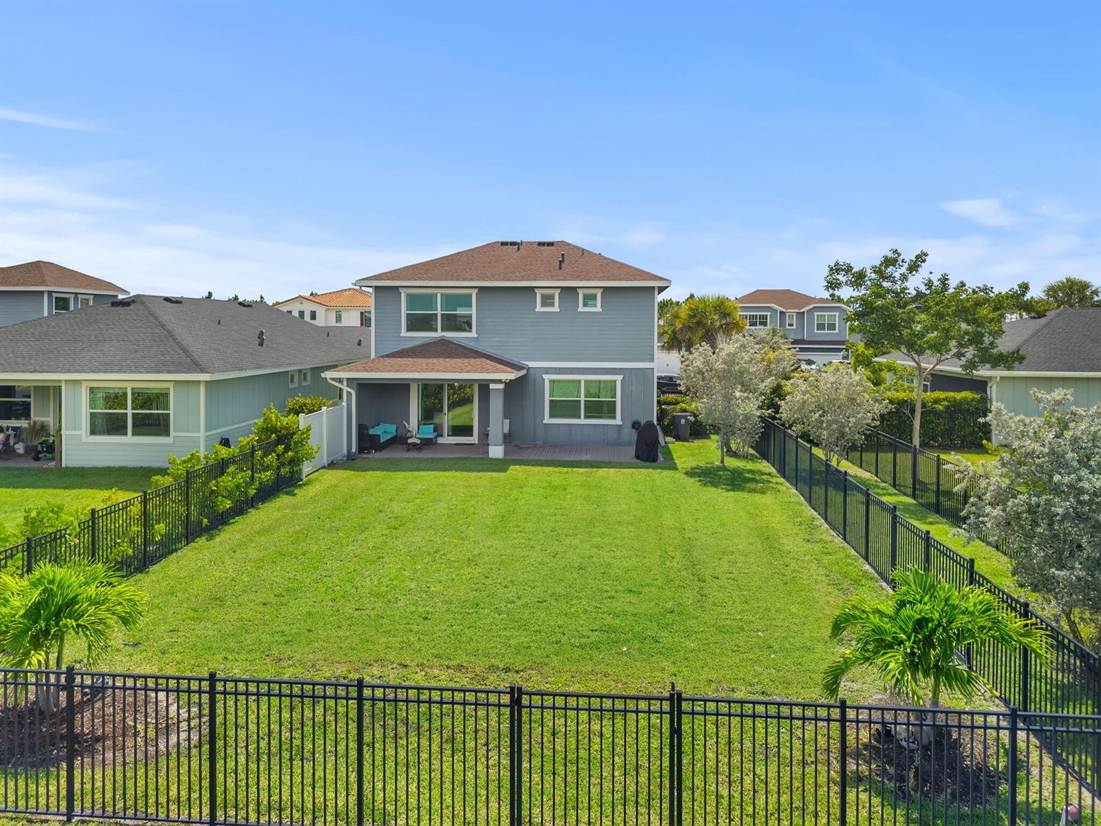 An aerial view shows the backyard of a two-story blue house with a fenced lawn — 1408 Wandering Willow Way, Loxahatchee FL 33470, LOXAHATCHEE, FL