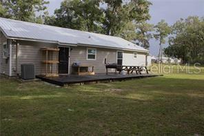 The exterior of a single-story house features light-colored siding, a metal roof, and a wooden deck — 11370 SW 175TH COURT, DUNNELLON, FL