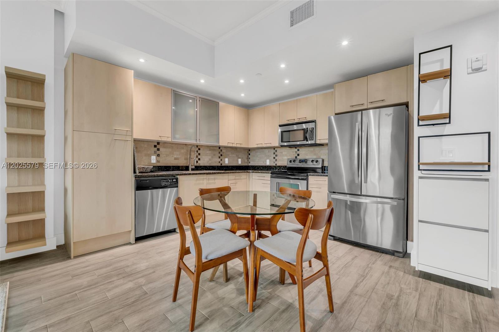A kitchen features light wood cabinets, stainless steel appliances, and a glass-topped dining table — 1350 NW 8th Ct # 207, Miami FL 33136, MIAMI, FL