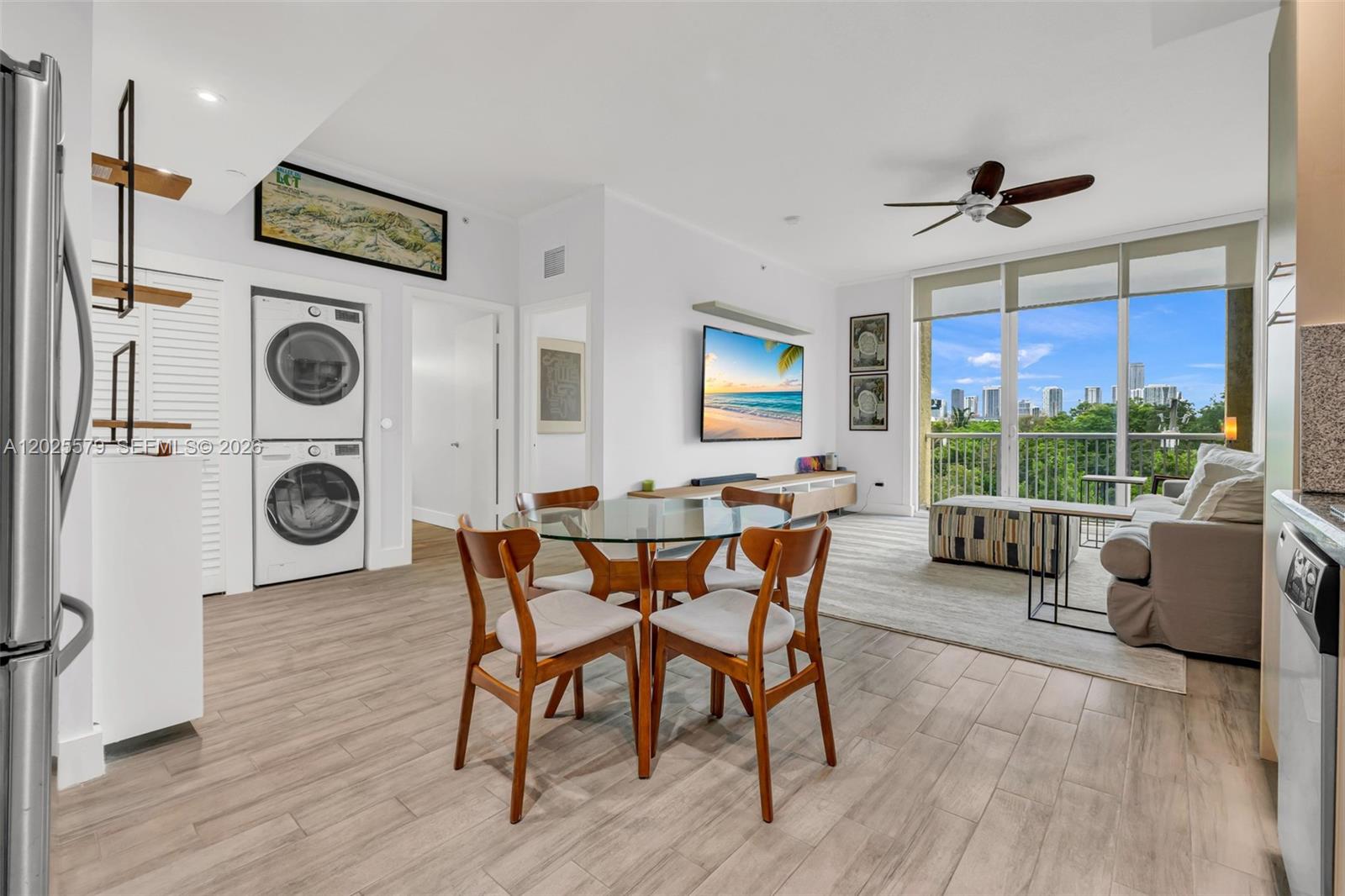 An open-concept living and dining area features a stacked washer-dryer, glass table, and balcony view — 1350 NW 8th Ct # 207, Miami FL 33136, MIAMI, FL