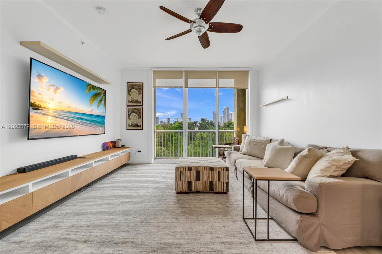 A living room features a large television, a beige sofa, and a balcony with city views — 1350 NW 8th Ct # 207, Miami FL 33136, MIAMI, FL
