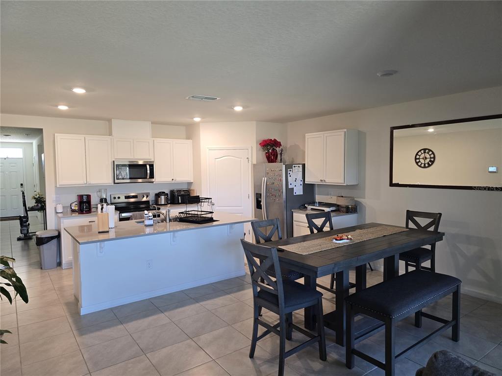 A kitchen with white cabinets and a central island sits next to a dining area — 873 AMBLESIDE DRIVE, HAINES CITY, FL