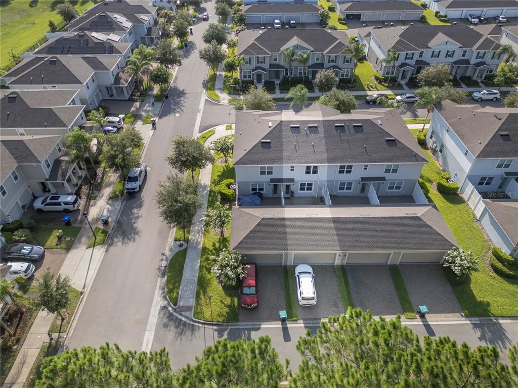 An aerial view shows a residential neighborhood with townhomes adjacent to a highway and forest — 6208 ARALIA IVY LANE, WINTER GARDEN, FL