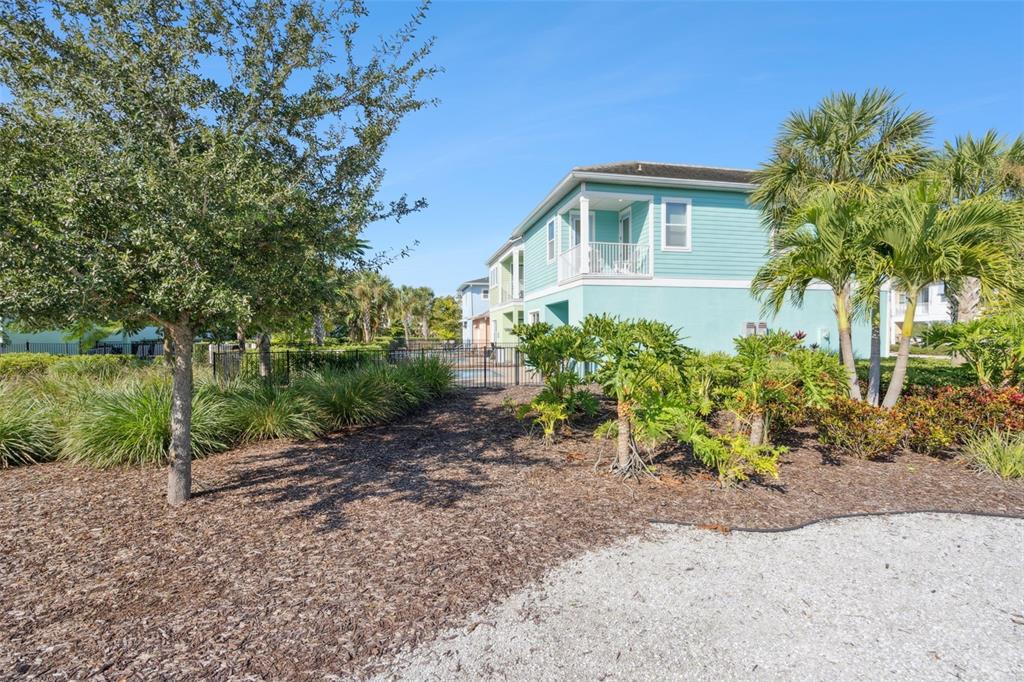A light blue two-story house stands behind a landscaped yard with trees and palm plants — 8082 KNEE DEEP ROAD, KISSIMMEE, FL